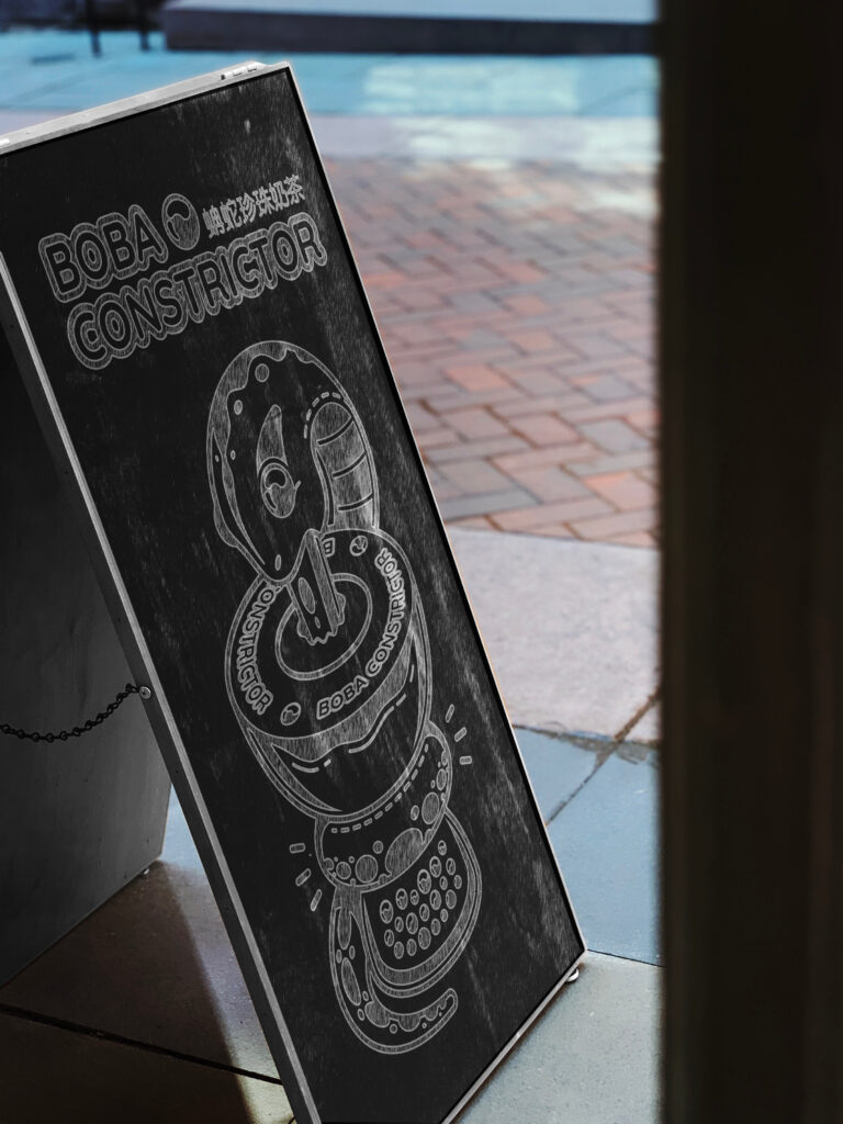 outside street photo of a Boba Constrictor logo and mascot on a chalkboard